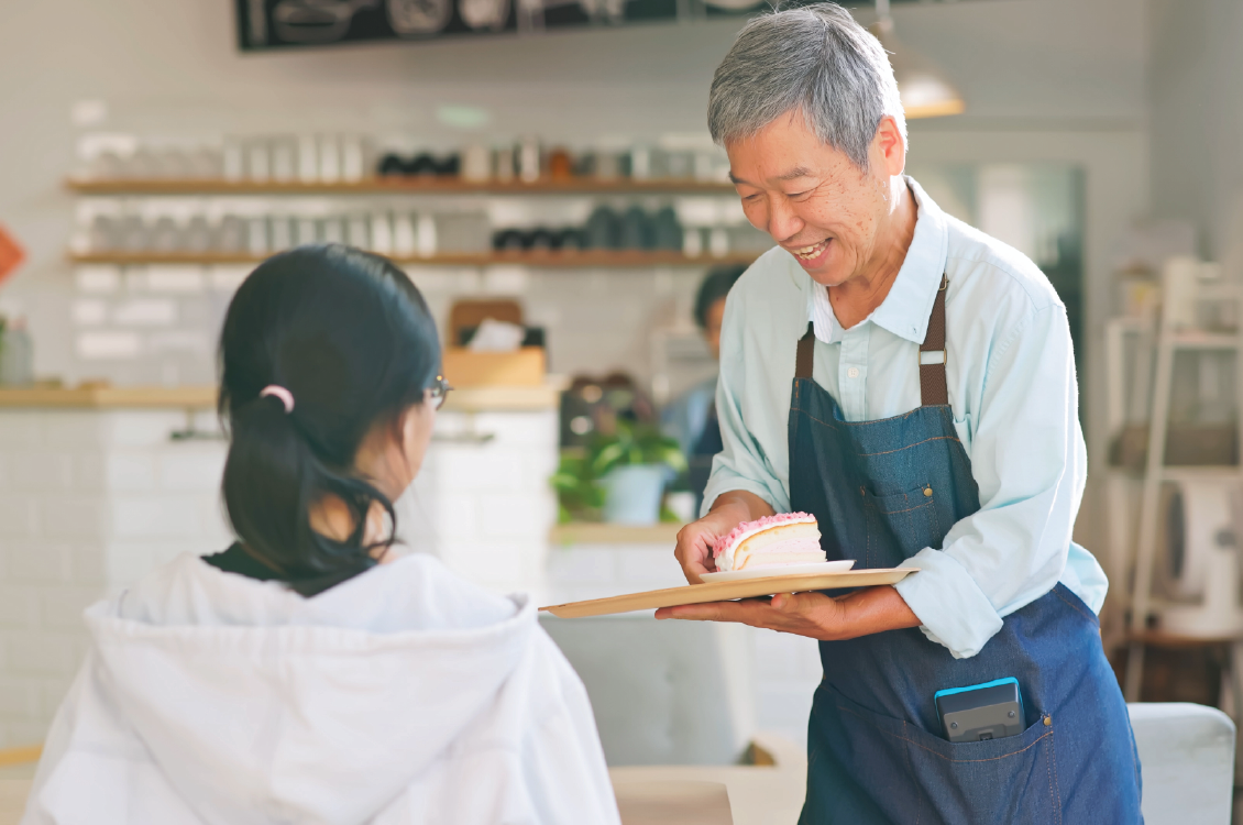 man in apron serving cake to customer
