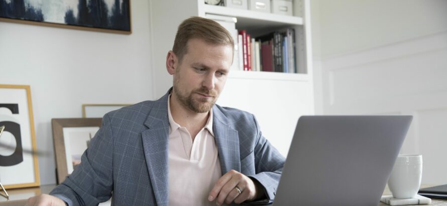 A man works on a laptop at a desk.