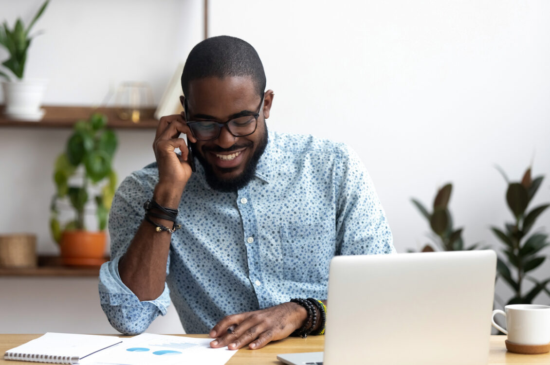 Man talks on phone at desk.