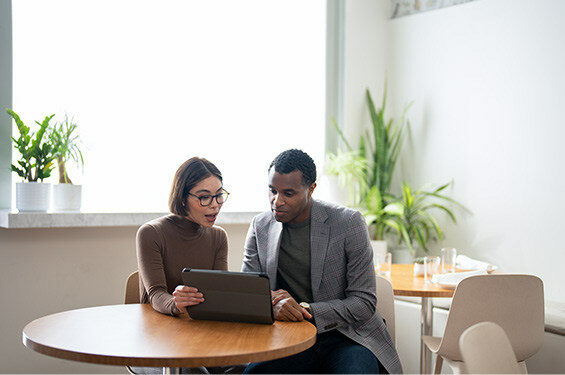 A woman and man discuss economic trends over a computer.
