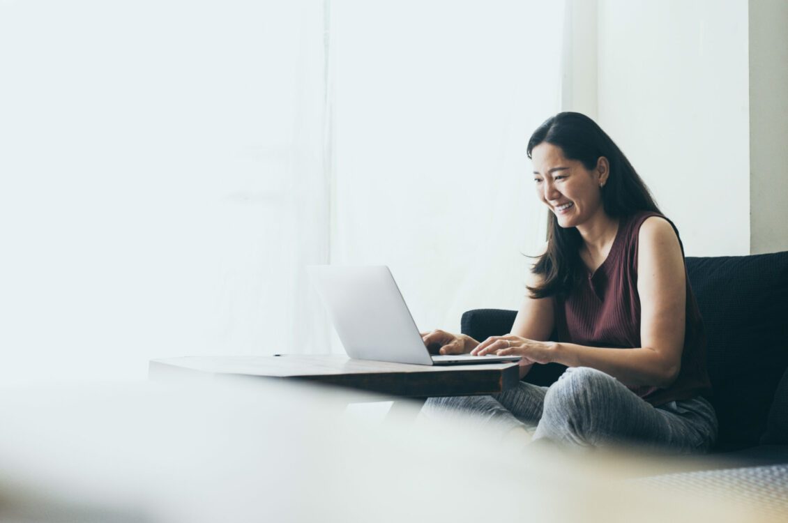 Woman searches the internet for retirement information while sitting on sofa.