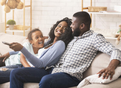 Joyful black family having fun together, relaxing on sofa at home.