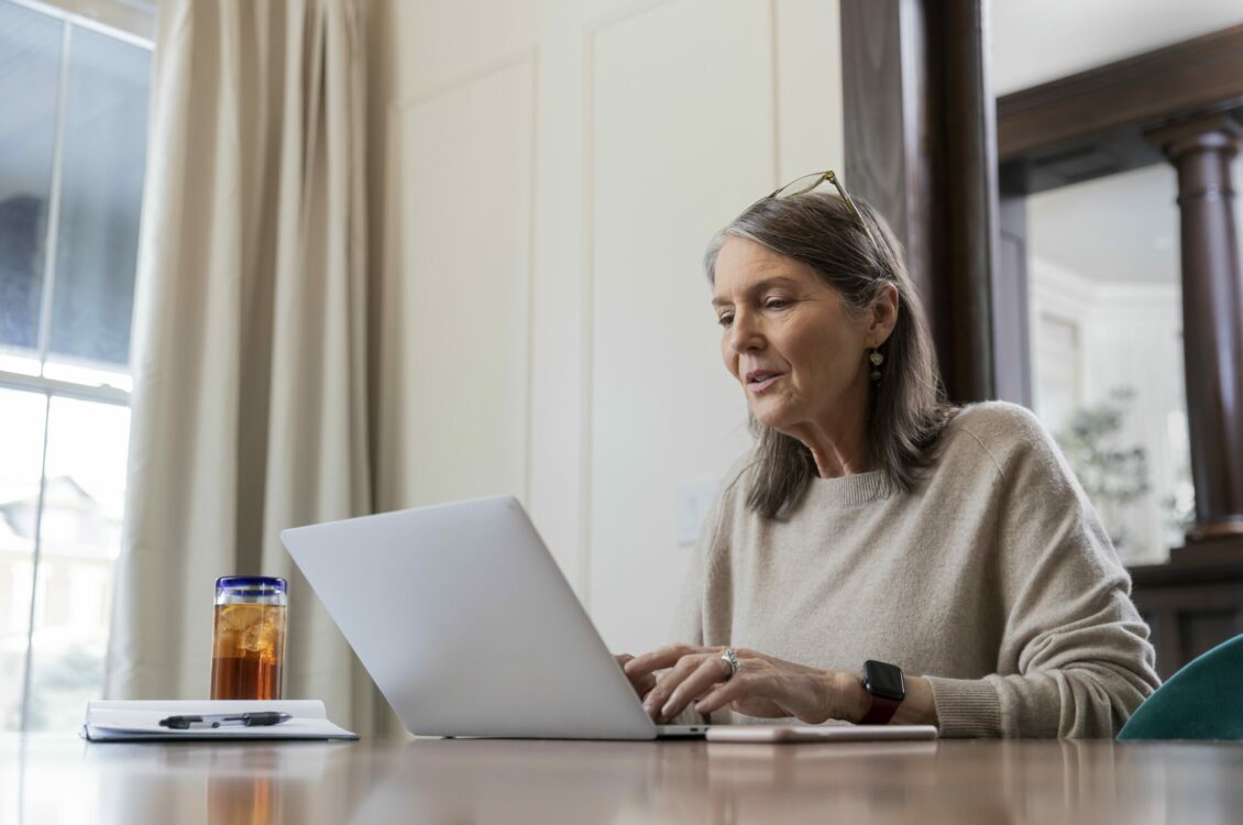 A mid-aged woman working on a laptop.