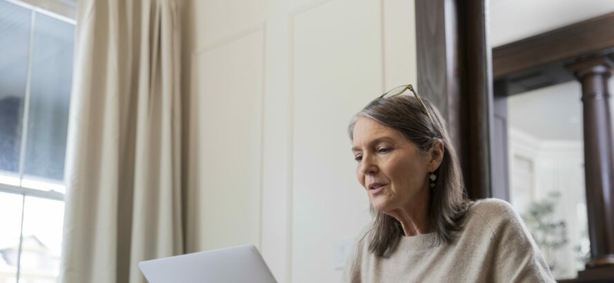 A mid-aged woman working on a laptop.