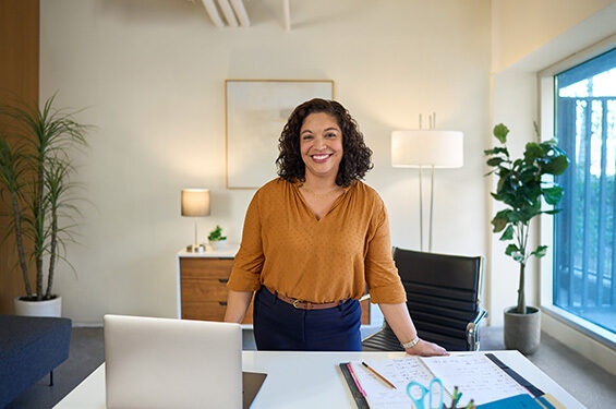 A woman standing behind their work desk.