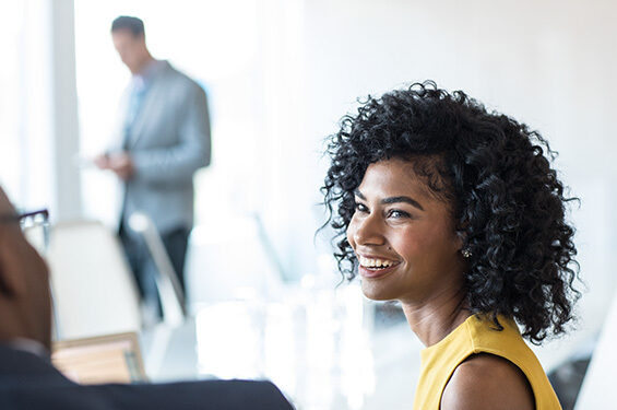 A lady smiling at another person.