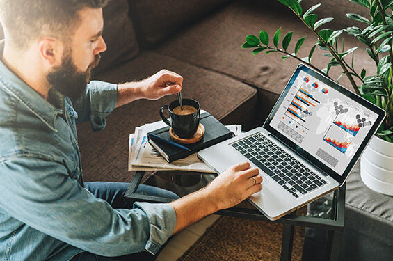 A person working on their laptop and stirring a cup of coffee.