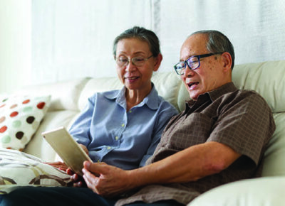An elderly couple sharing a tablet device.