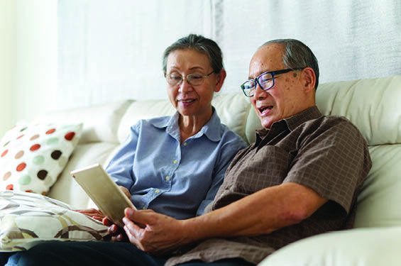 An elderly couple sharing a tablet device.