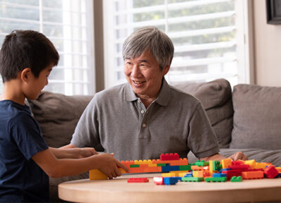 A man and a young boy building structures with colorful Lego blocks.