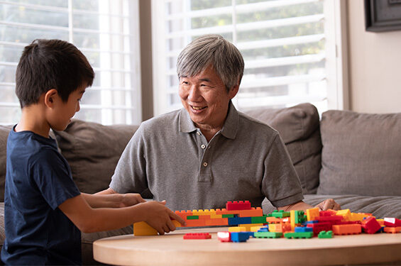 A man and a young boy building structures with colorful Lego blocks.