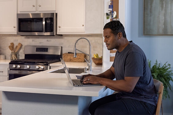 Man working on laptop at a kitchen counter