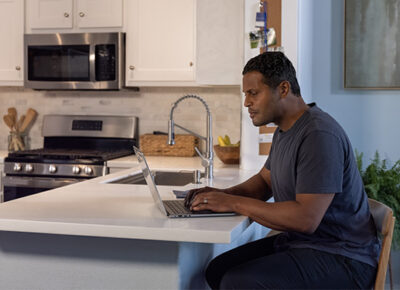 Man working on laptop at a kitchen counter