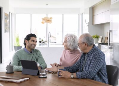 A smiling man shows an elderly couple something on a tablet.